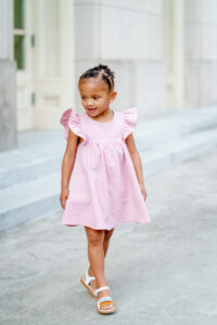 Small girl stands out side of building in macon for family photography.